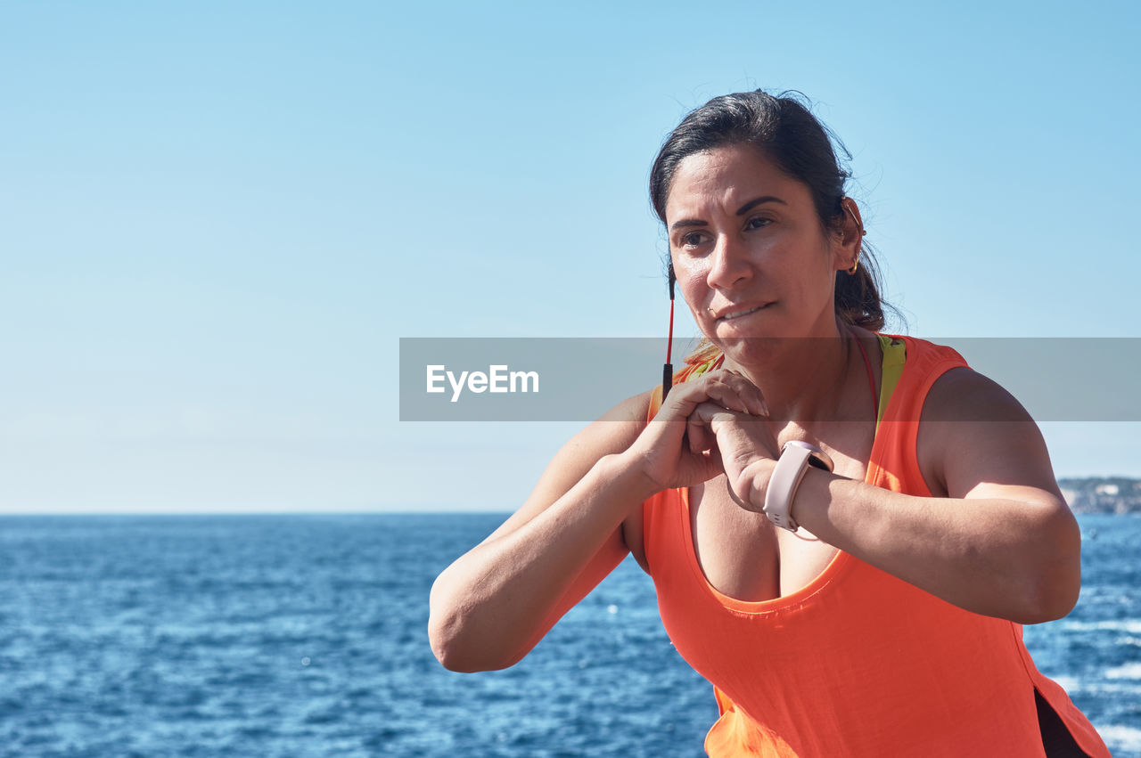 Fitness woman 40-50 years , in sports set training weights gym exercises, in front of the water	