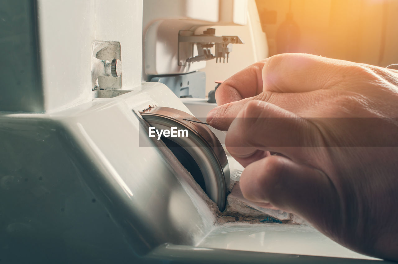 Hands of a man sharpening a needle on a grinding wheel