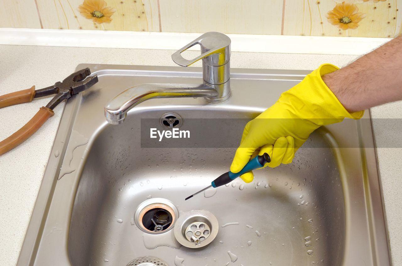 Cropped image of person repairing sink