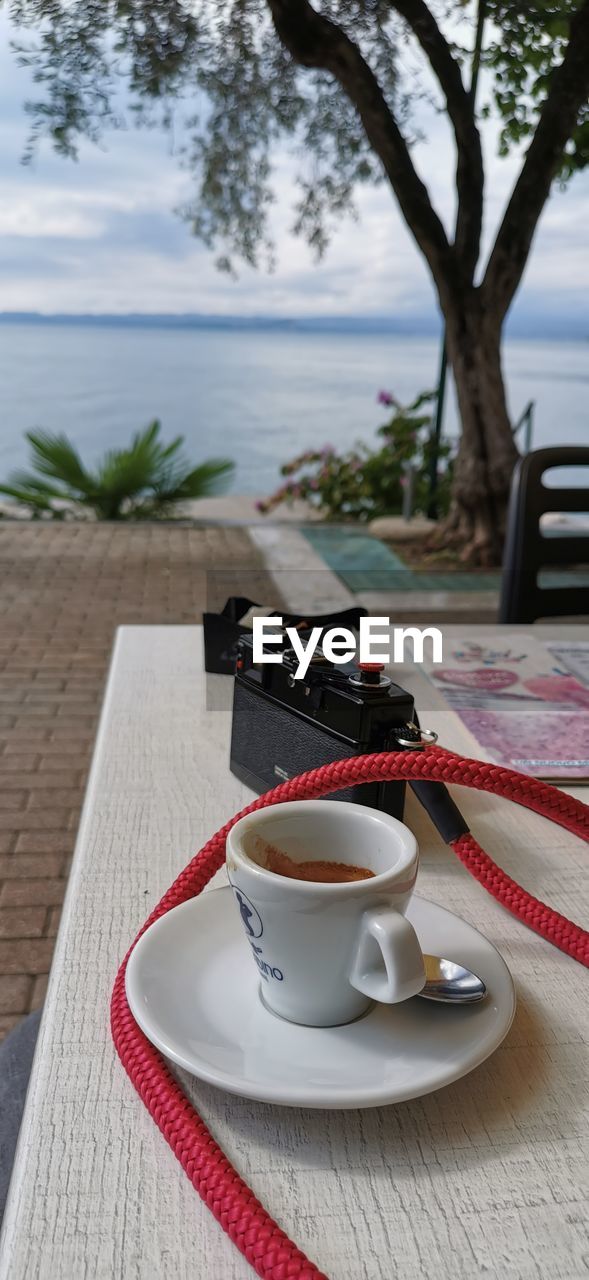 CUP OF COFFEE ON TABLE BY GLASS