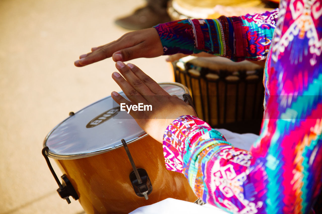 Cropped image of street musician playing drum on street