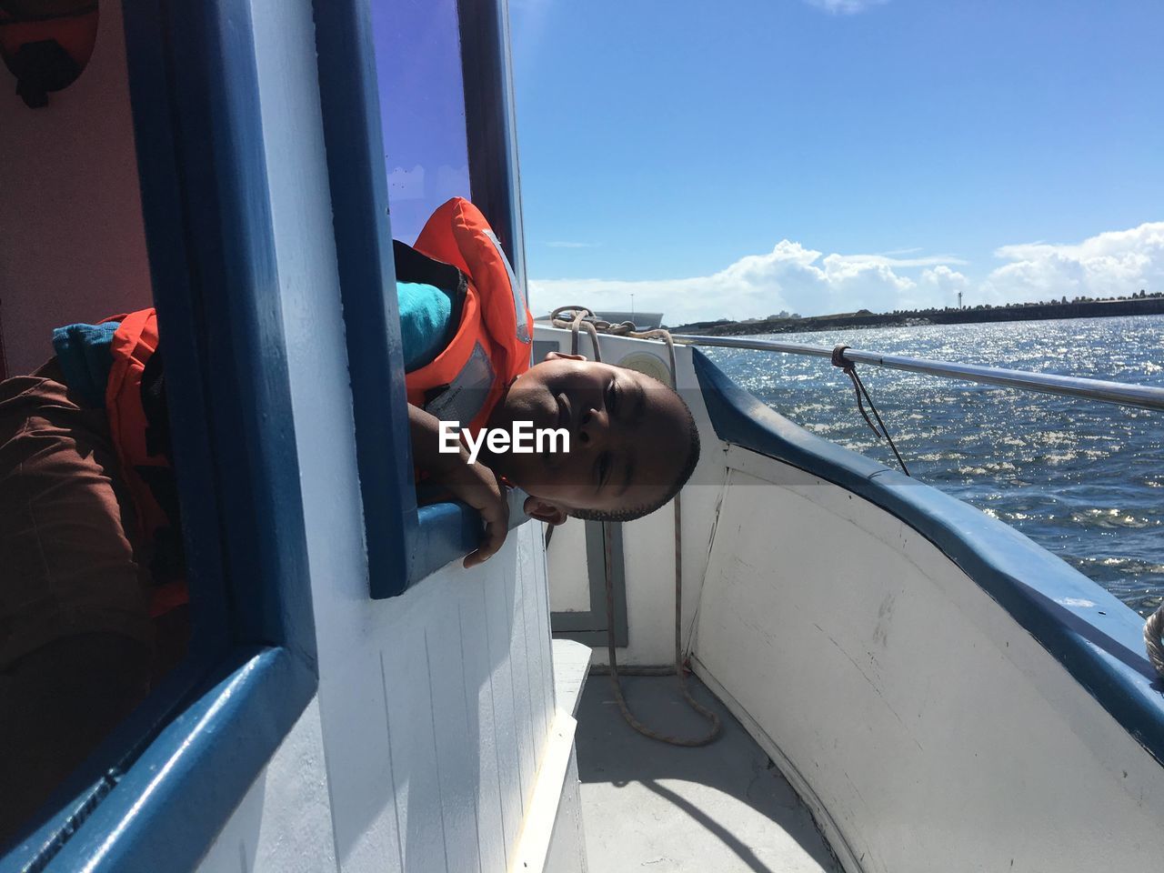 Young boy looking out of a boat window smiling 