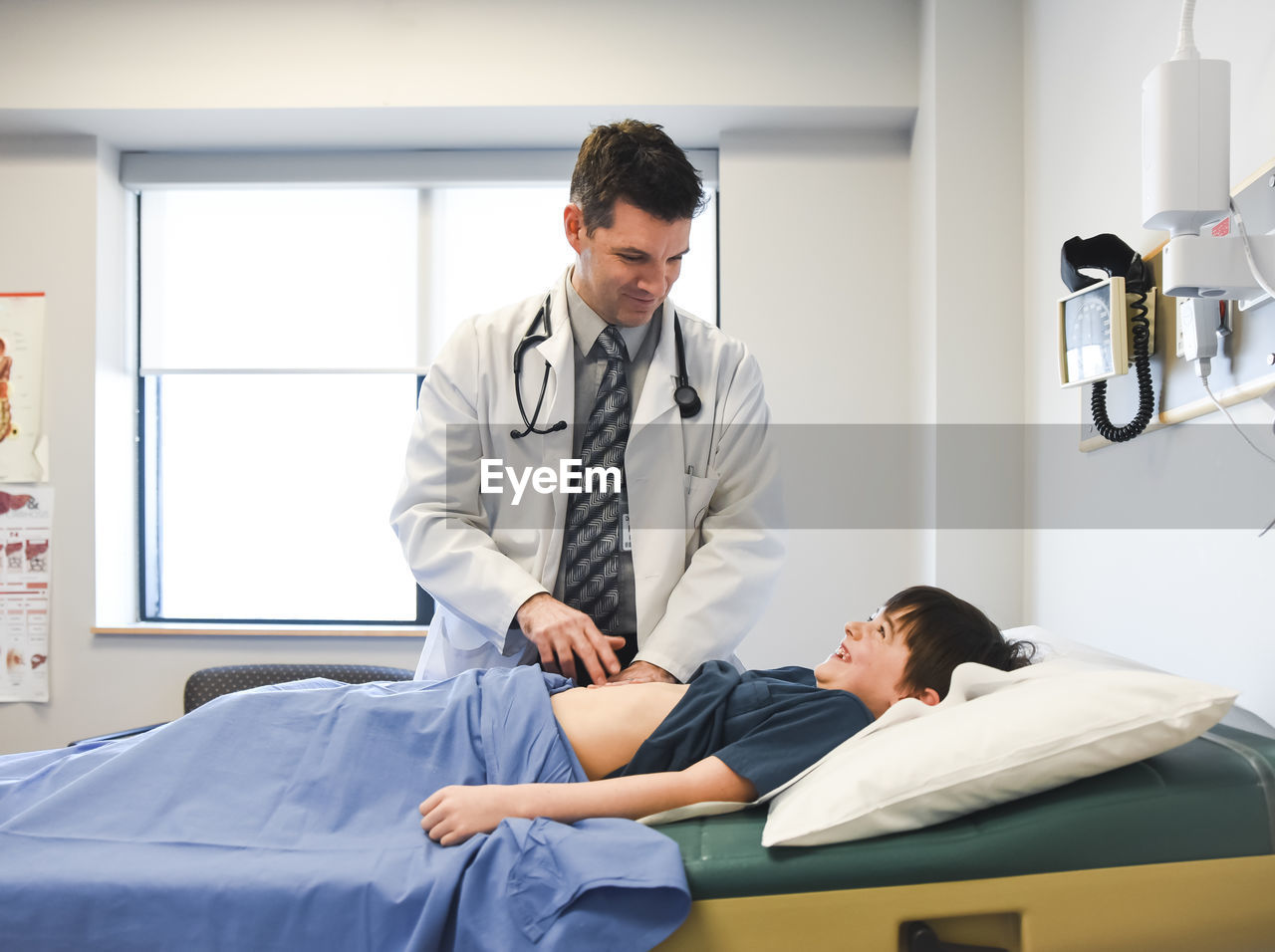 Doctor examining abdomen of child on an exam table of a clinic.