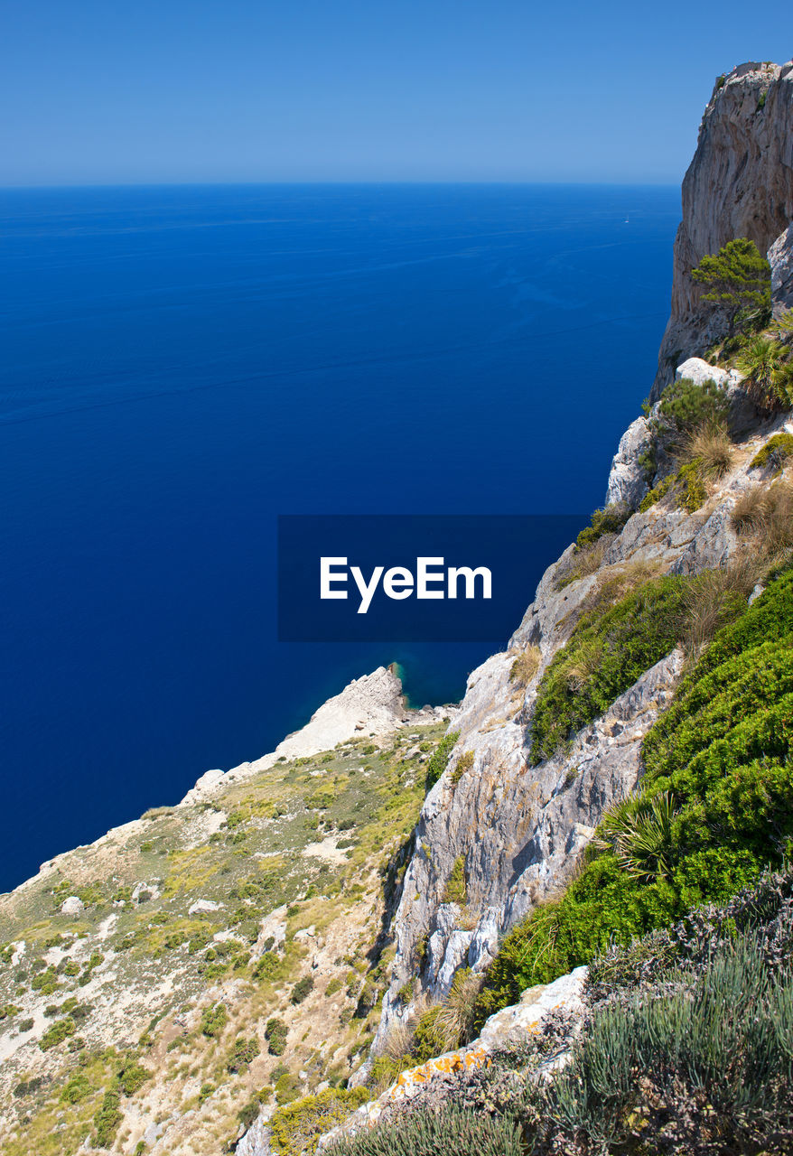 SCENIC VIEW OF SEA AND MOUNTAIN AGAINST BLUE SKY