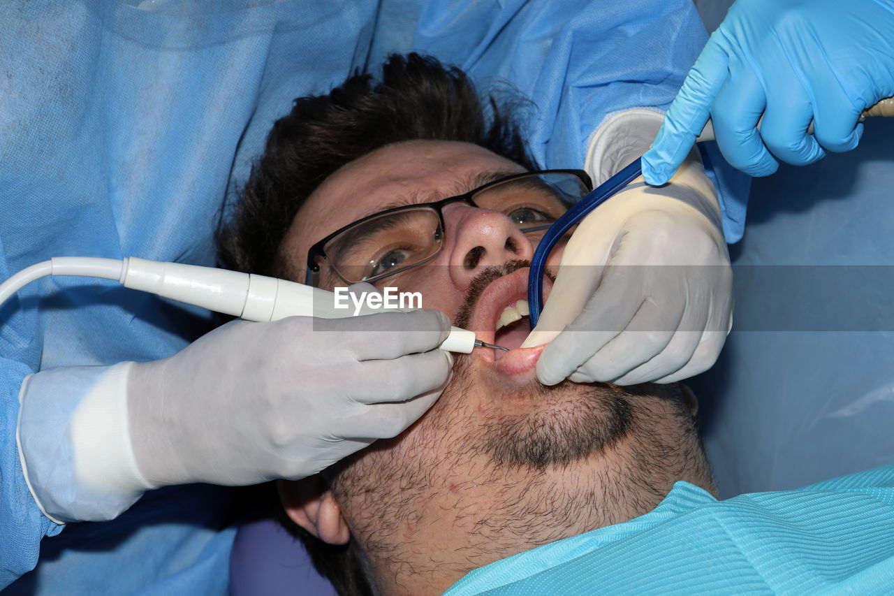 A man with a slight beard undergoing a dental procedure