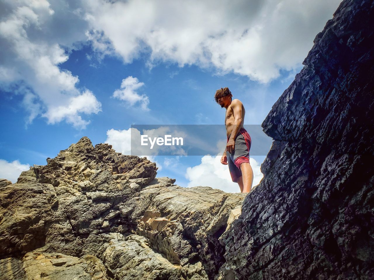 Low angle view of man standing on rock against sky