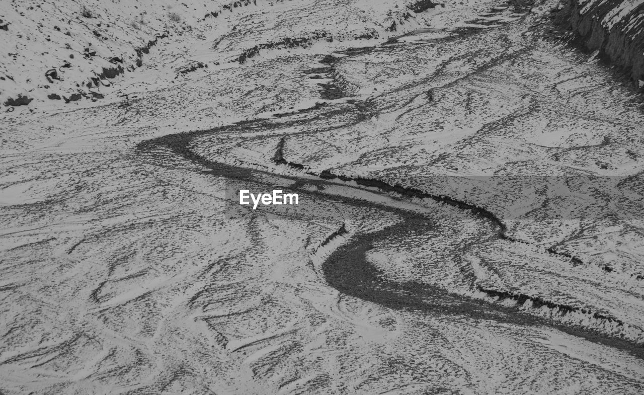 HIGH ANGLE VIEW OF TIRE TRACKS ON BEACH