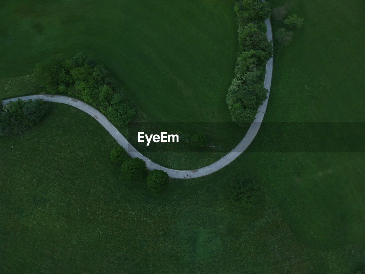 Aerial view of curved road amidst grassy field