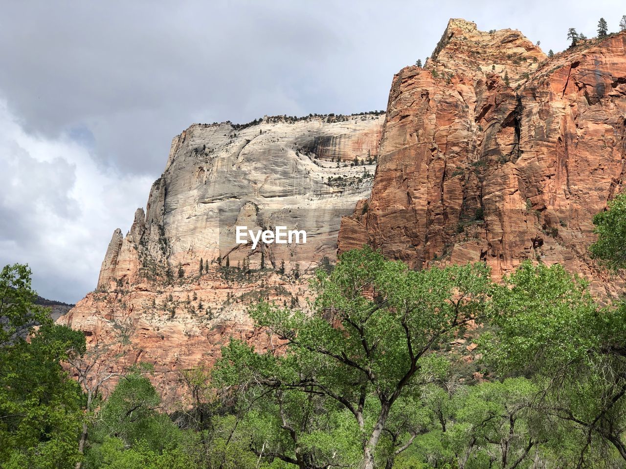 Low angle view of rocks on mountain against cloudy sky