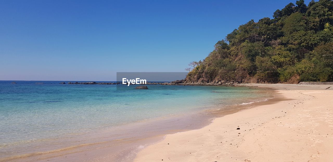 Scenic view of beach against clear blue sky