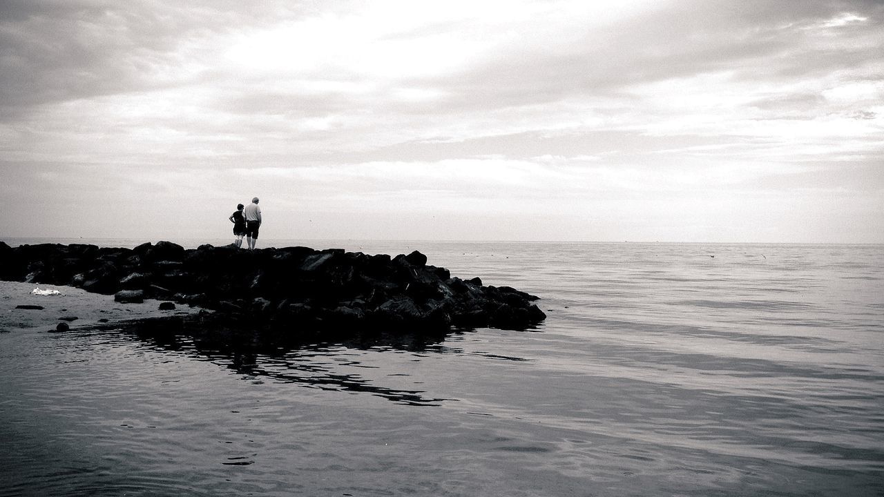 Couple looking at sea view while standing on rocks