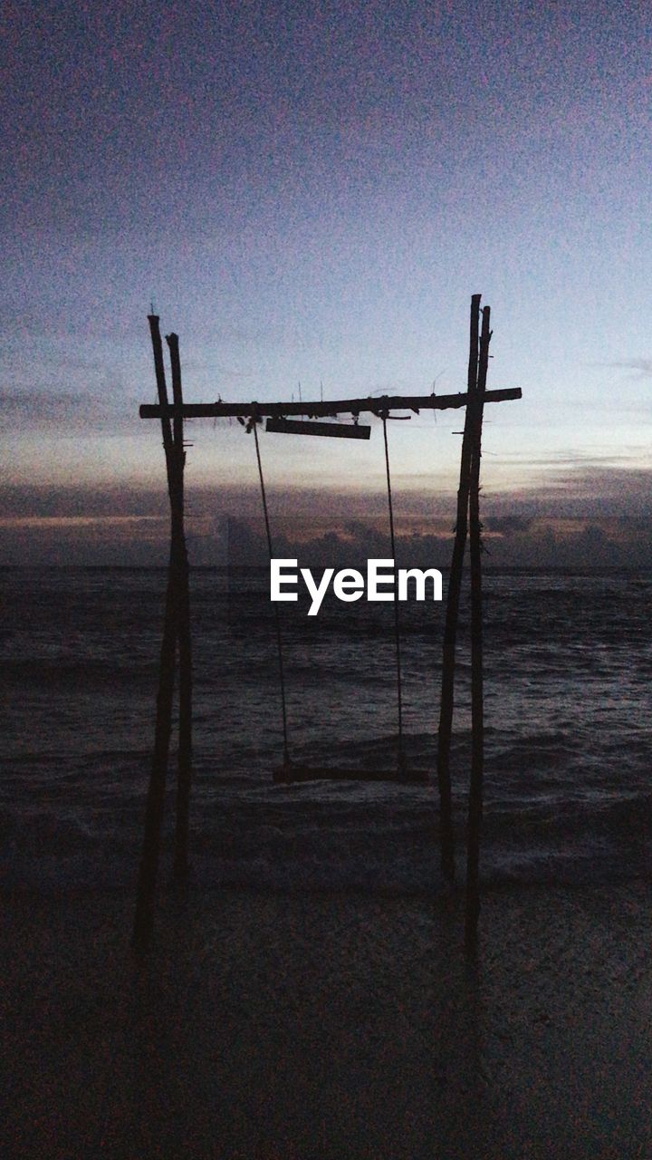 SILHOUETTE WOODEN POSTS ON FIELD AGAINST SKY