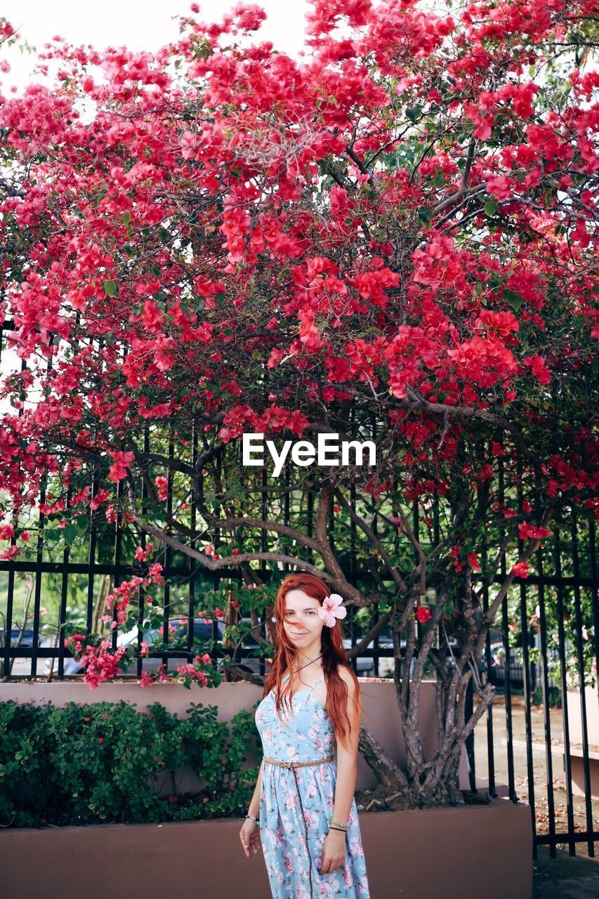 YOUNG WOMAN STANDING WITH RED FLOWERS