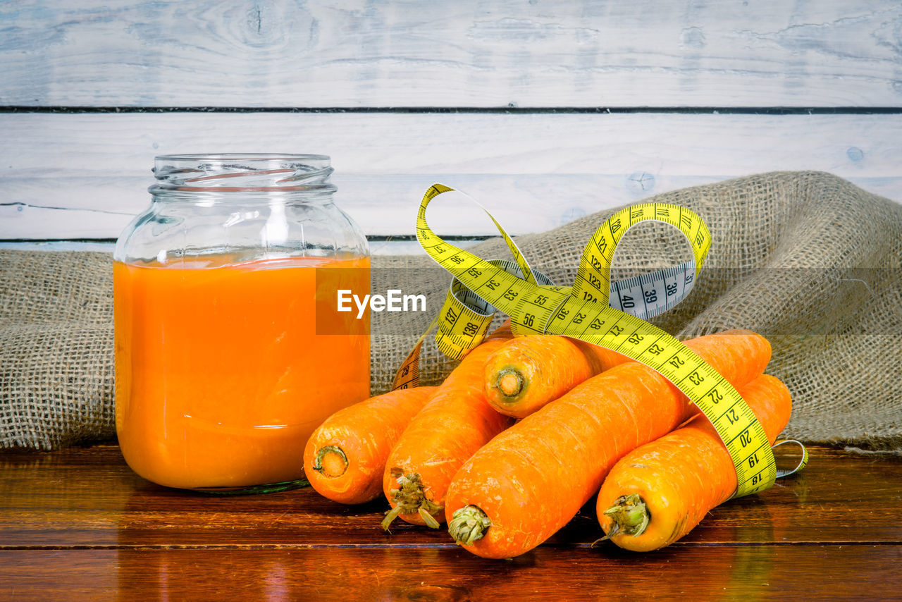 Carrot by juice and yellow measure tape on table