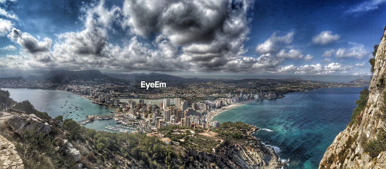 AERIAL VIEW OF CITYSCAPE AGAINST CLOUDY SKY