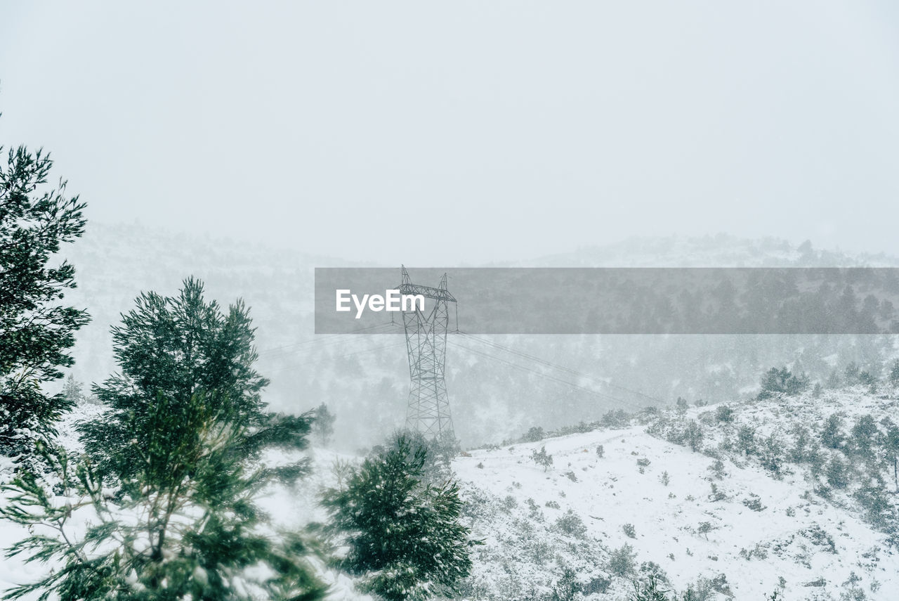 Electricity pylon on snow covered landscape