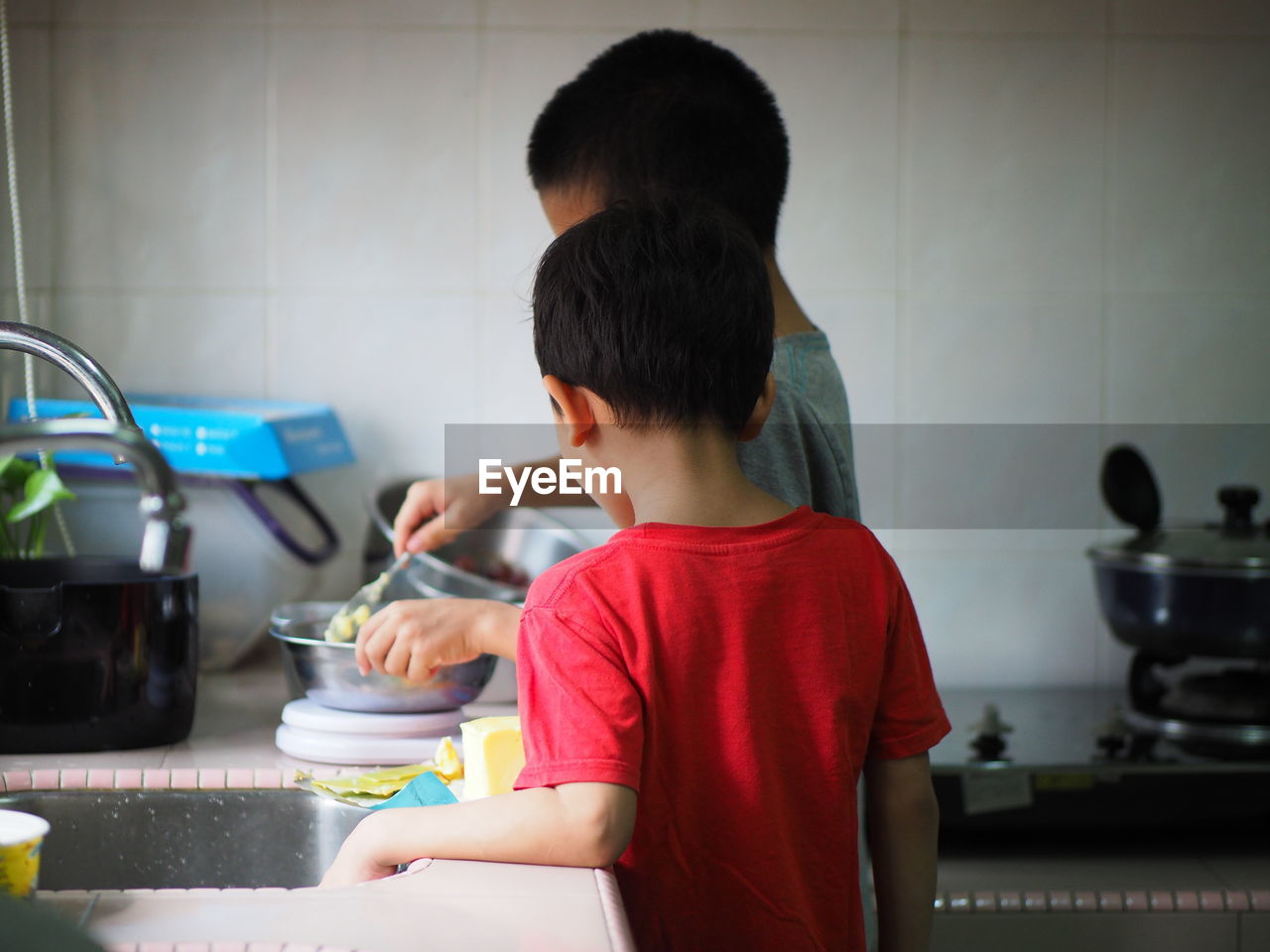 Siblings preparing food in kitchen