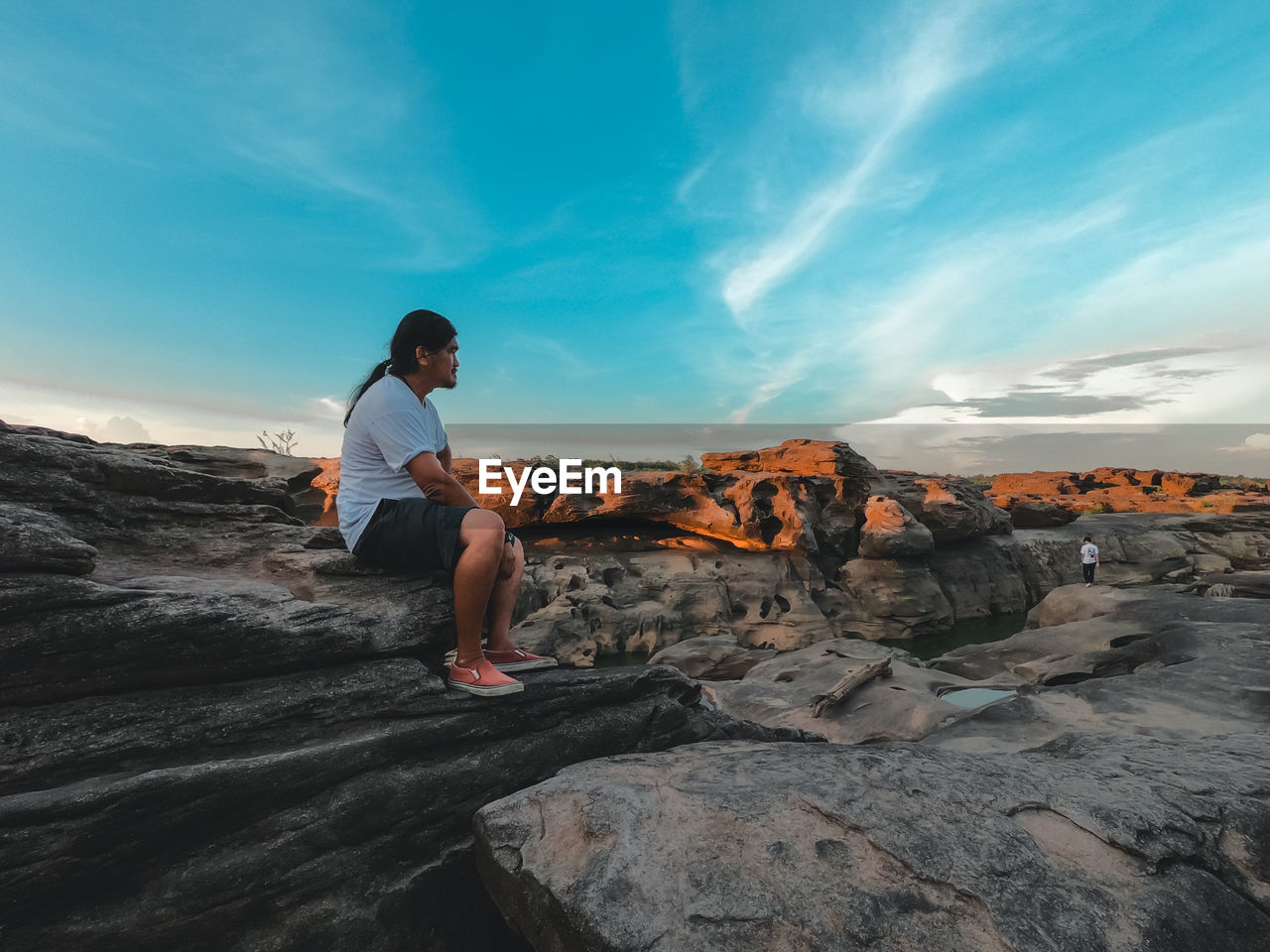 Full length of man standing on rock against sky