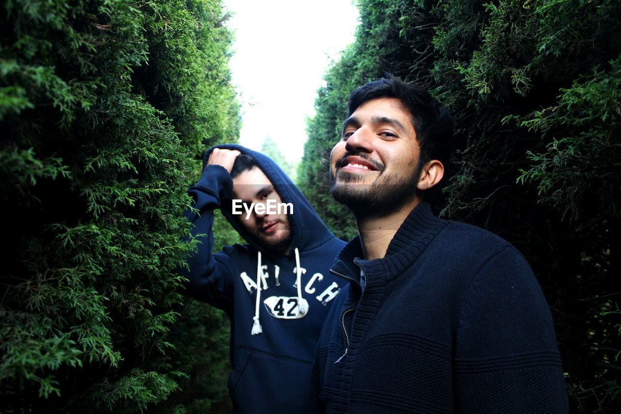 Portrait of young man with friend amidst trees