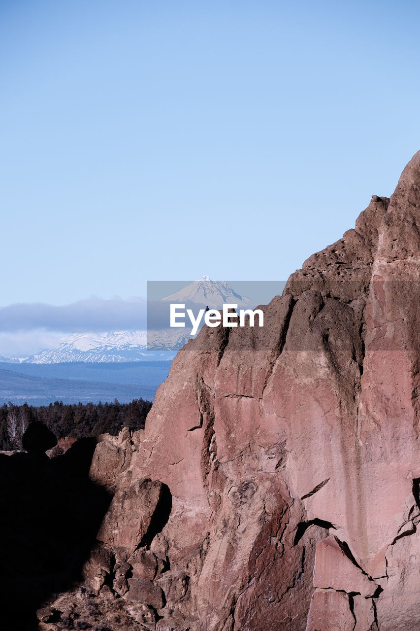 Scenic view of mountain against blue sky and rock climber