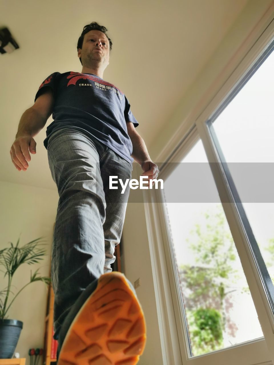 LOW ANGLE VIEW OF YOUNG MAN LOOKING AT WINDOW
