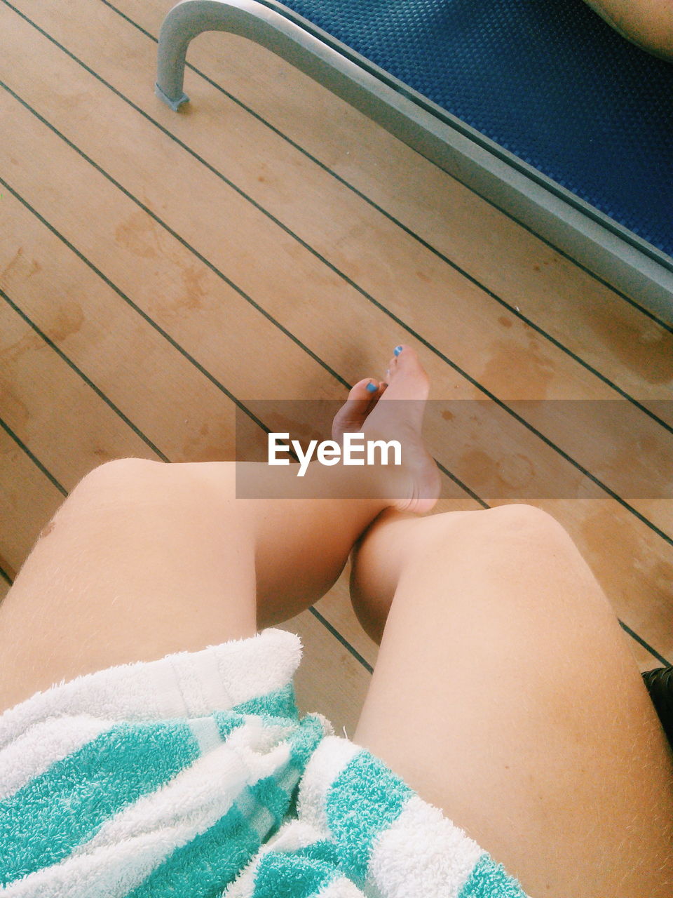 Low section of woman sitting on floorboard at poolside