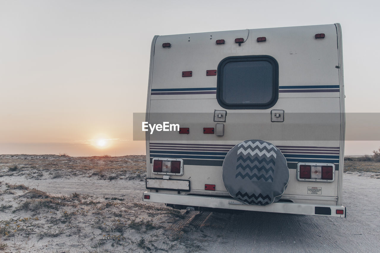 The back of the trailer, which stands on the sandy curb against the horizon and sunset on the coast