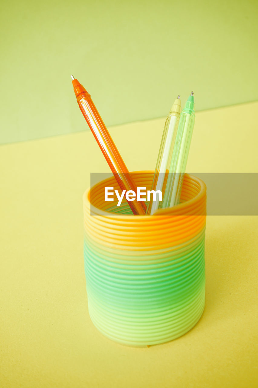 high angle view of multi colored pencils in container against yellow background