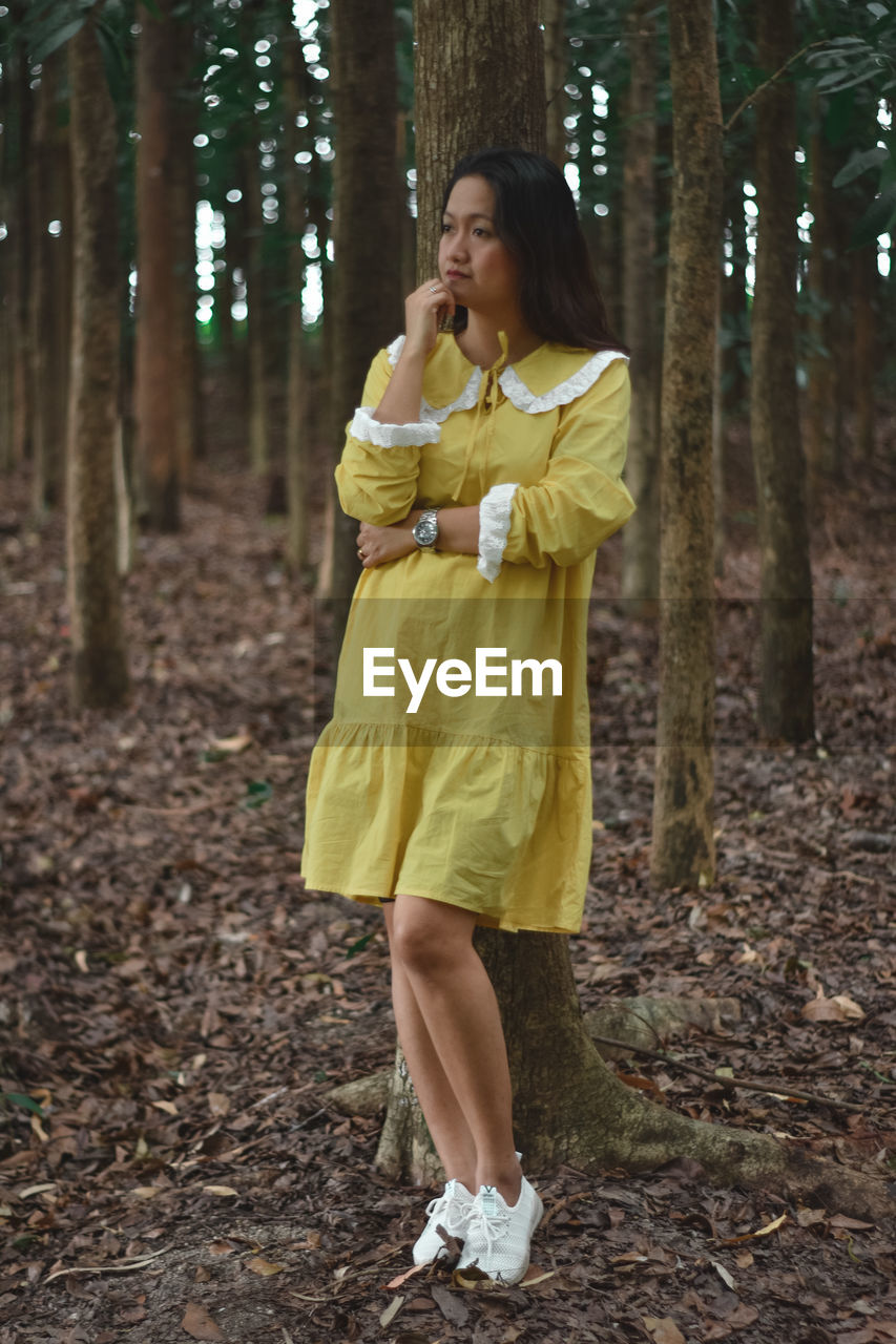 Full length of woman standing on tree trunk in forest