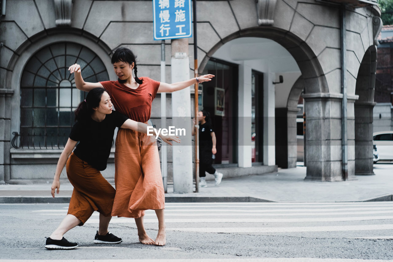 FULL LENGTH OF MAN AND WOMAN ON STREET AGAINST BUILDINGS