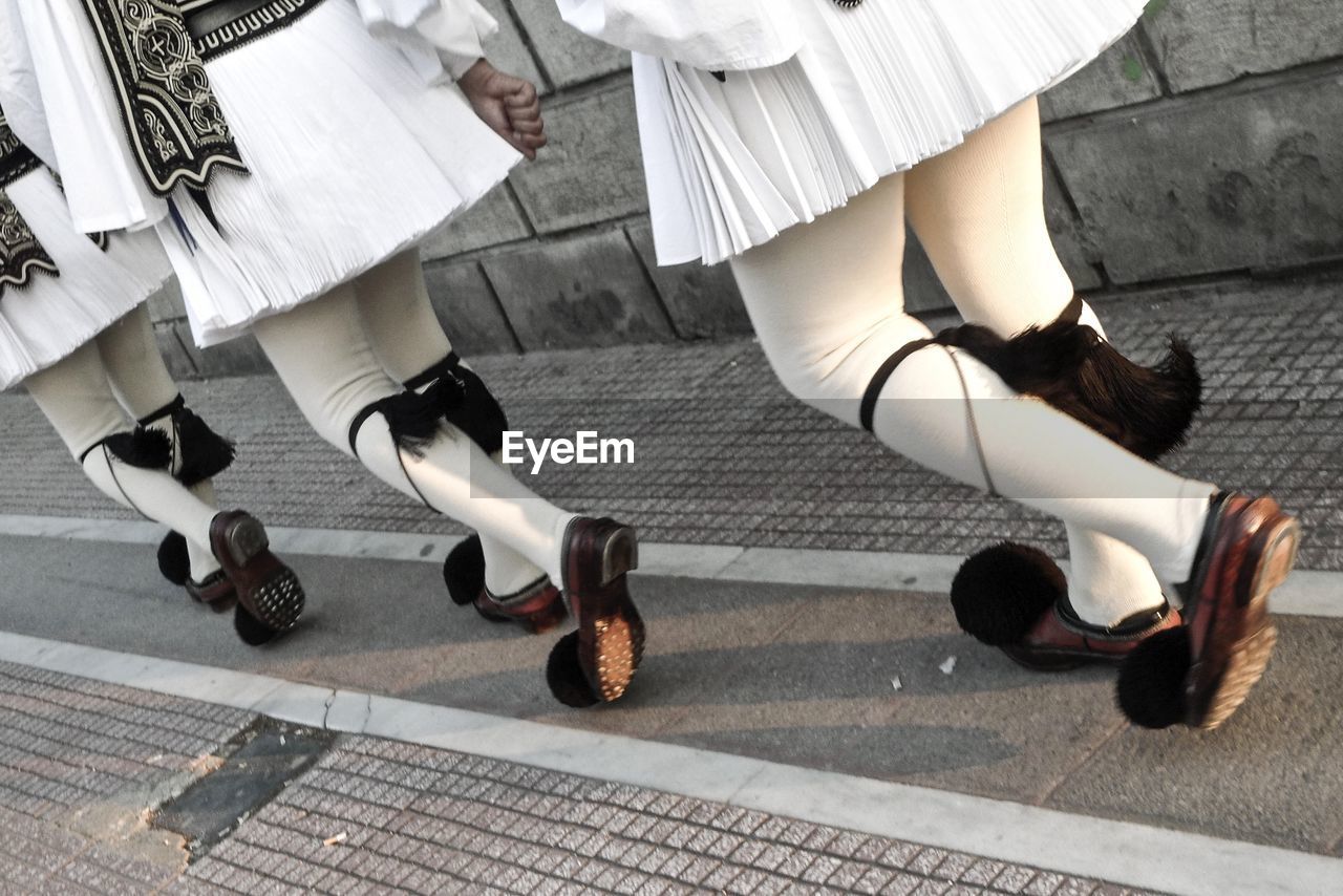 Low section of women wearing uniform while walking on footpath