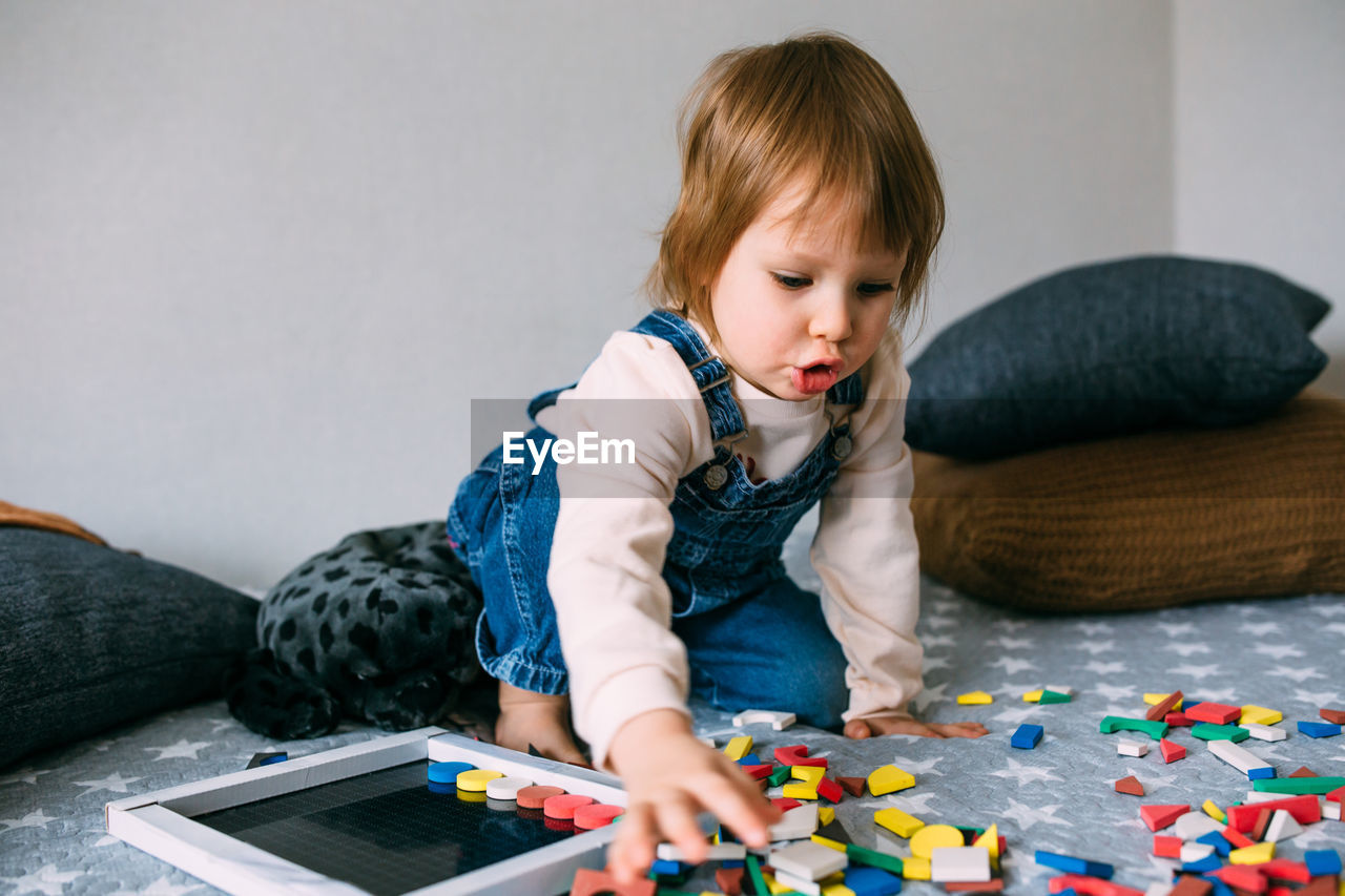 Child plays at home an educational game with a multi-colored magnetic puzzle