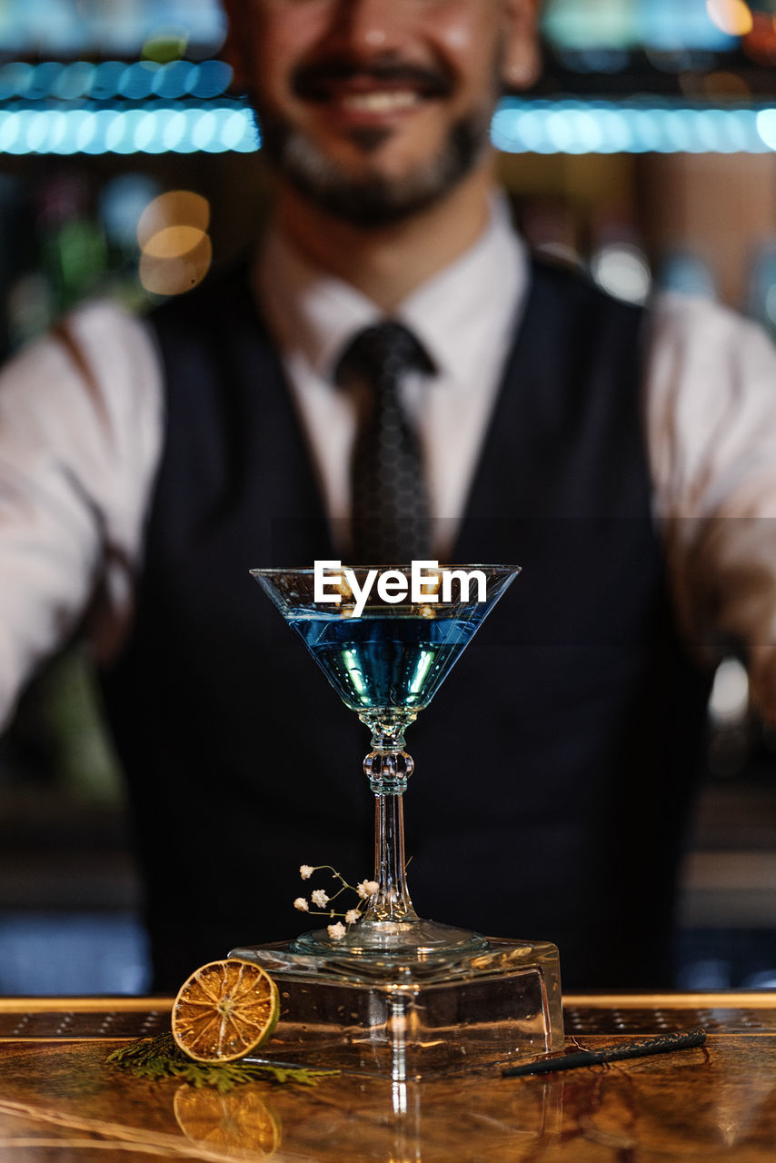 Midsection of man holding wine glass on table