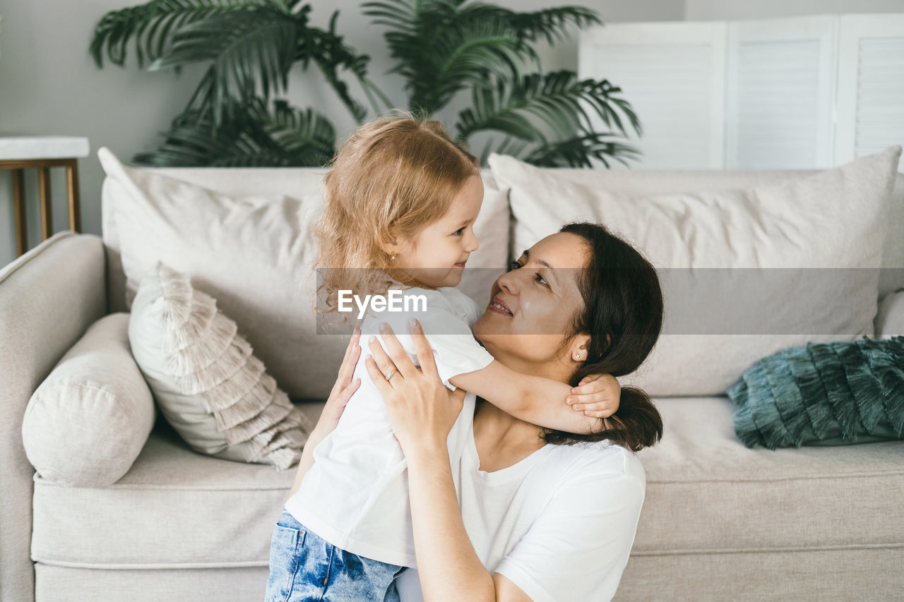 A mother gently hugs her four-year-old daughter.