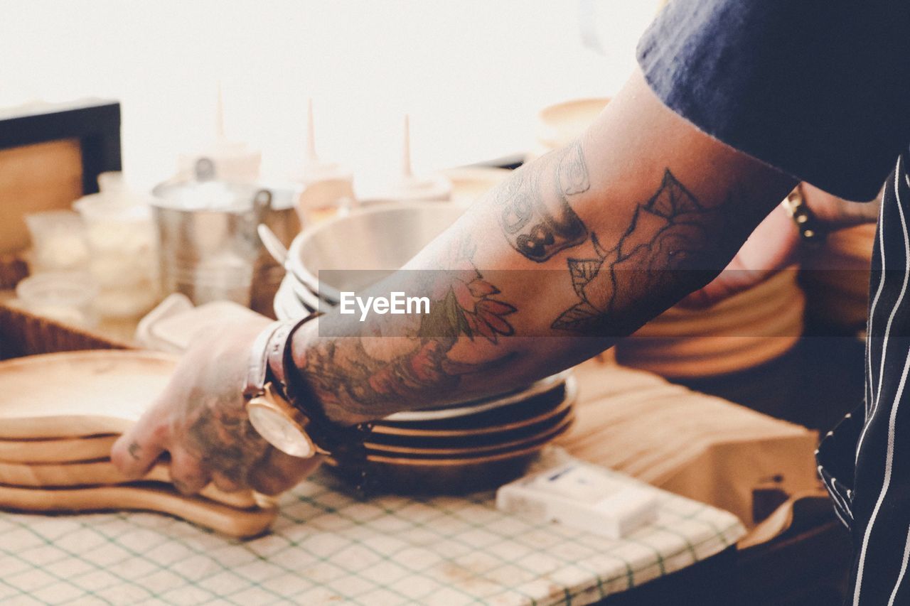 Close-up of man with tattoo on hand working in kitchen 