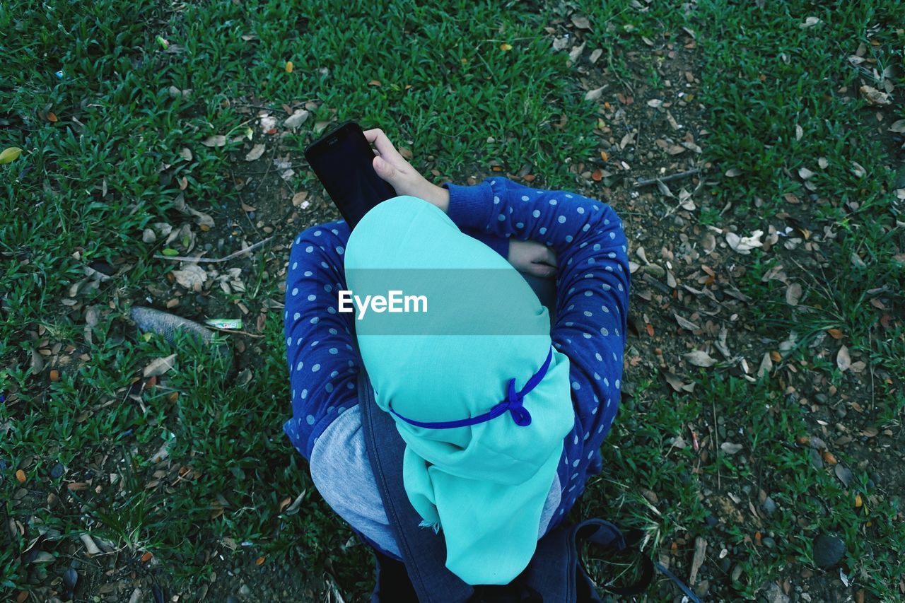 Directly above shot of woman using mobile phone on grassy field