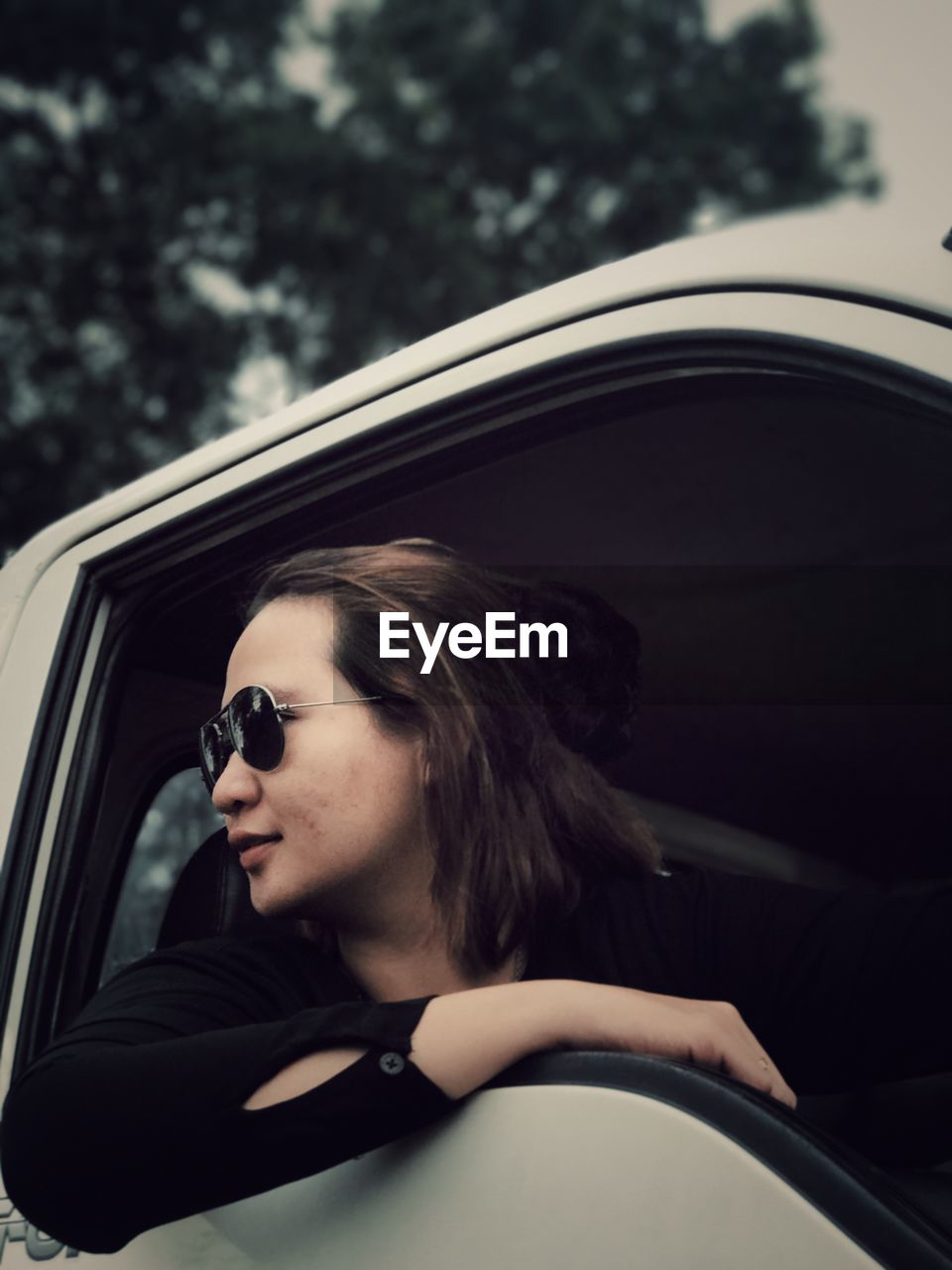 Woman in sunglasses looking through window of car