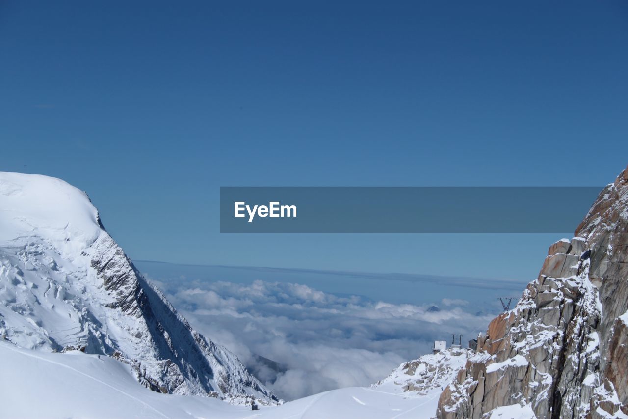 Scenic view of snowcapped mountains against clear blue sky