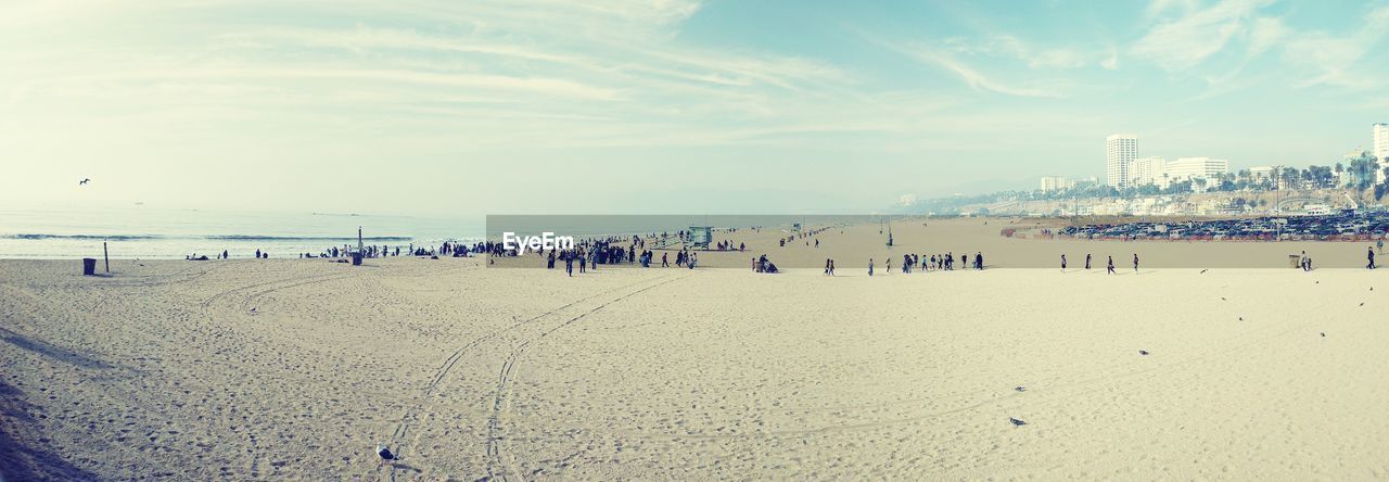 People at beach against sky during sunset