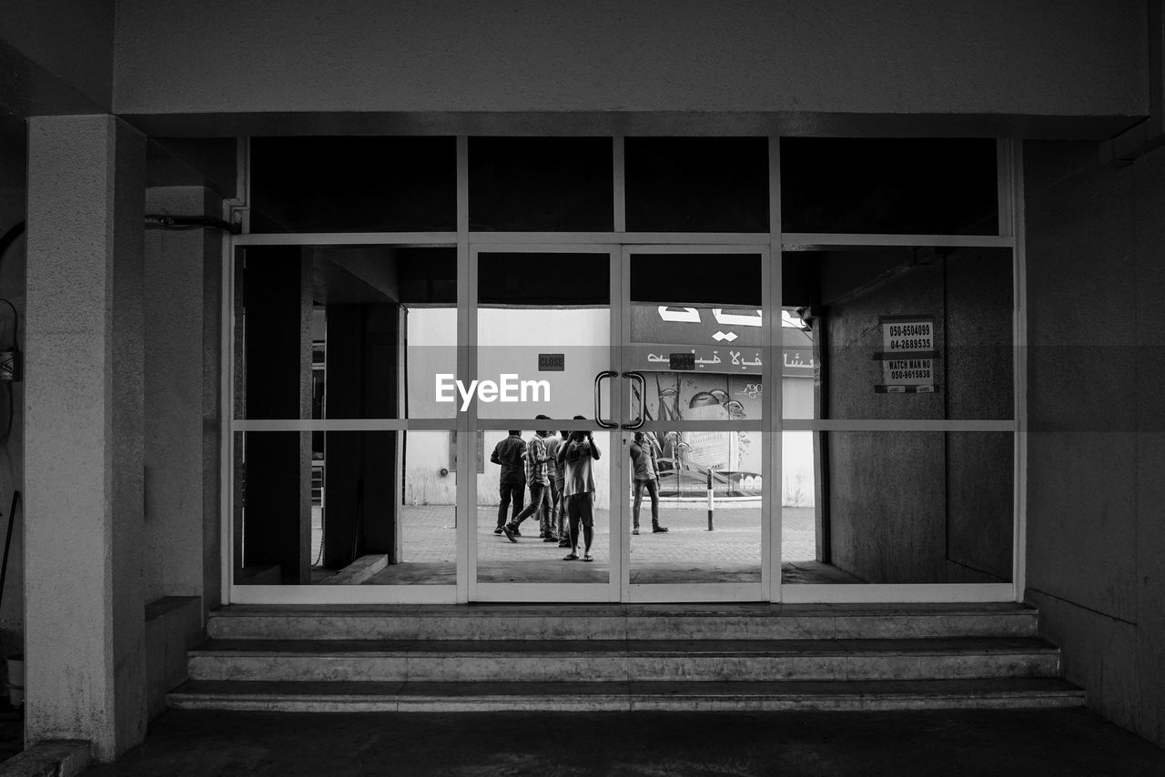 REAR VIEW OF WOMAN WITH BICYCLE ON BUILDING