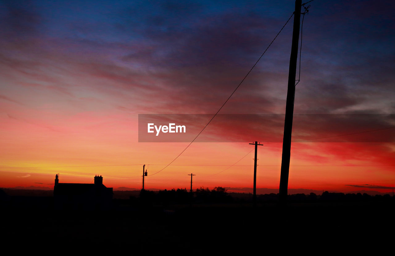 Silhouette electricity pylon against sky during sunset