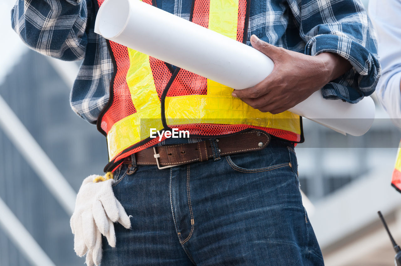 MIDSECTION OF MAN WORKING ON UMBRELLA