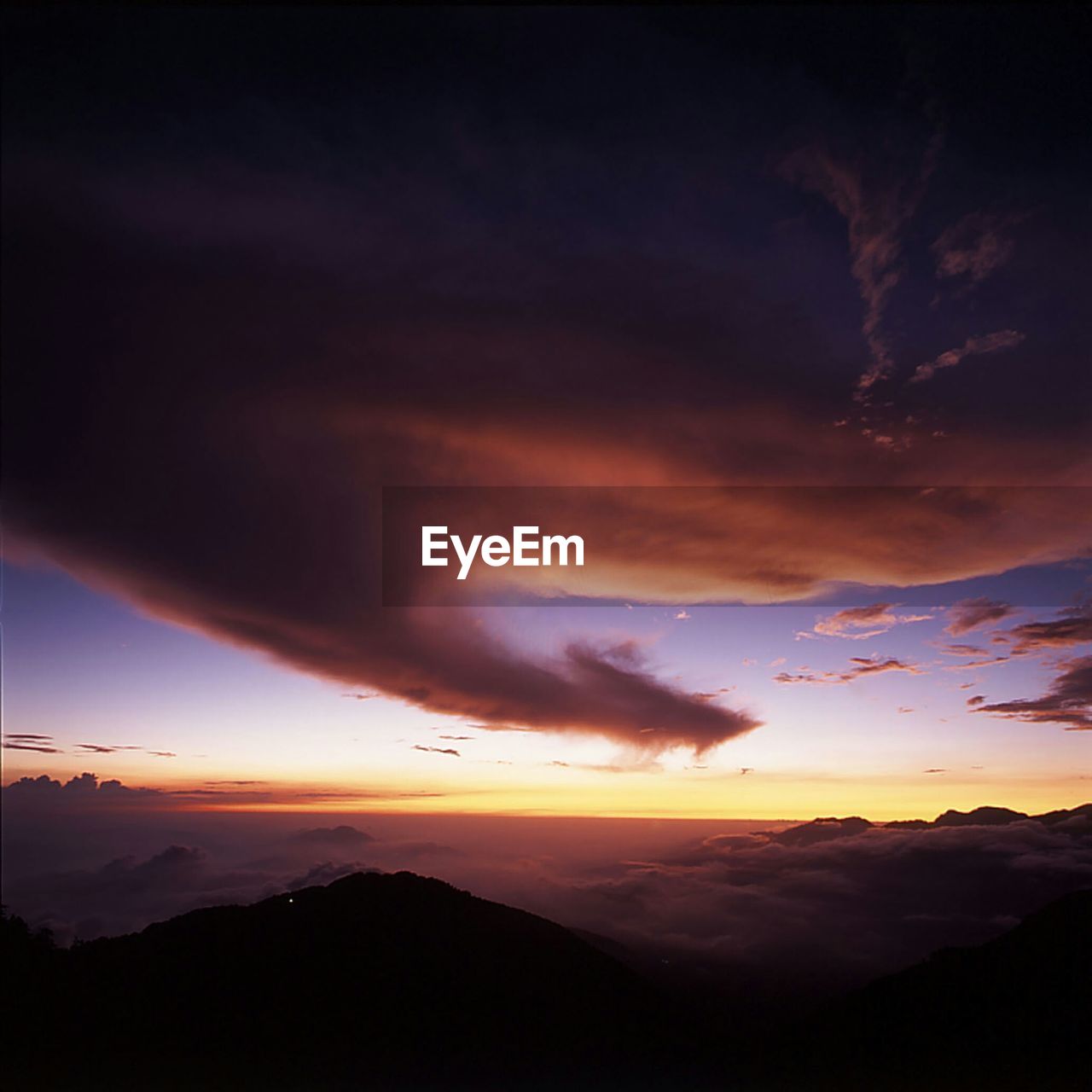 SCENIC VIEW OF MOUNTAINS AGAINST CLOUDY SKY AT SUNSET