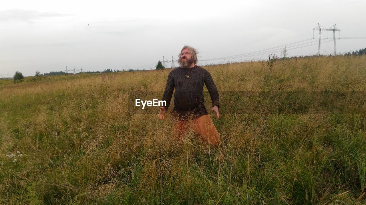 REAR VIEW OF MAN STANDING ON FIELD