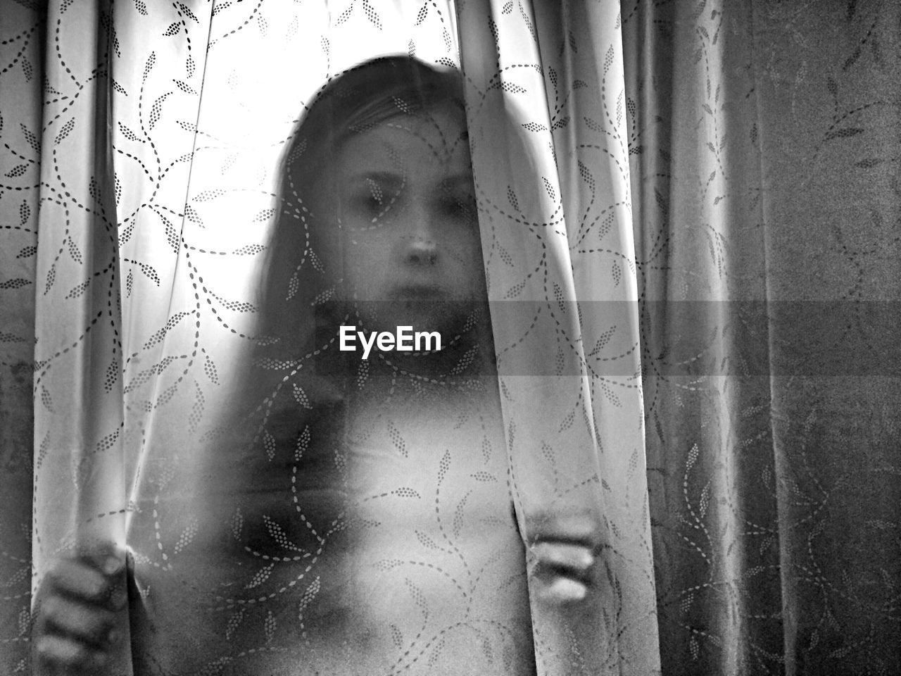 Girl seen through transparent curtain at home