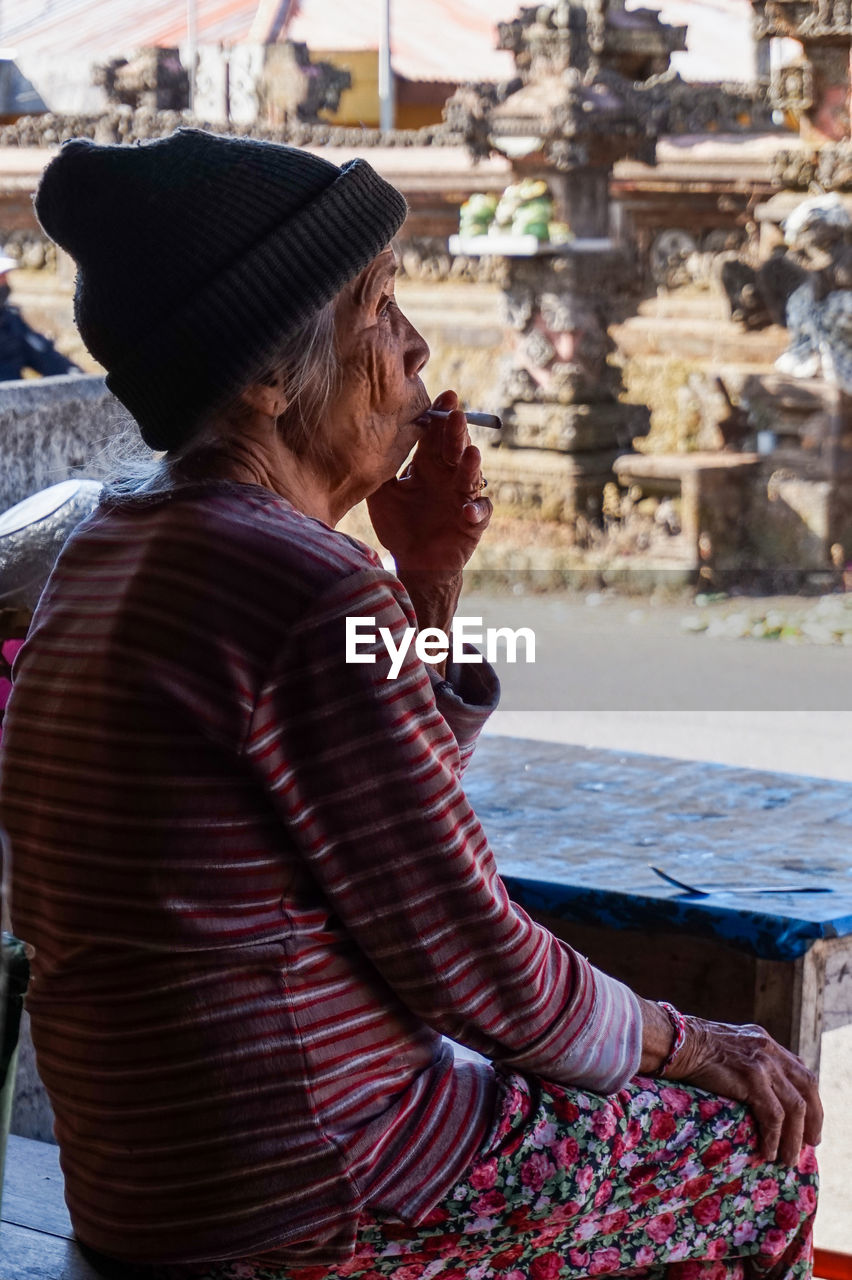 SIDE VIEW OF WOMAN SITTING AT AN ABANDONED