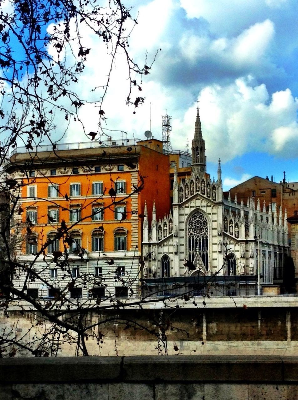 Cathedral by residential building against cloudy sky