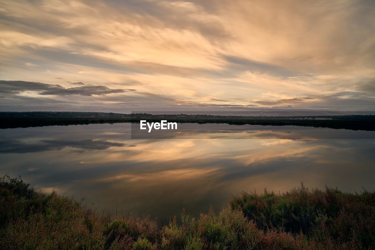 water, sky, cloud, reflection, beauty in nature, environment, scenics - nature, nature, morning, tranquility, landscape, lake, dawn, plant, sunrise, tranquil scene, land, no people, dramatic sky, grass, sun, outdoors, horizon, sunlight, travel destinations, non-urban scene, beach, travel, tree, twilight, idyllic, cloudscape, shore, tourism, atmospheric mood, summer, reservoir, orange color