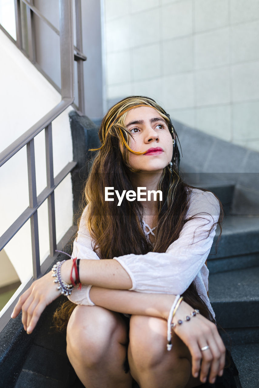 Hippie thoughtful young woman with long hair sitting on steps