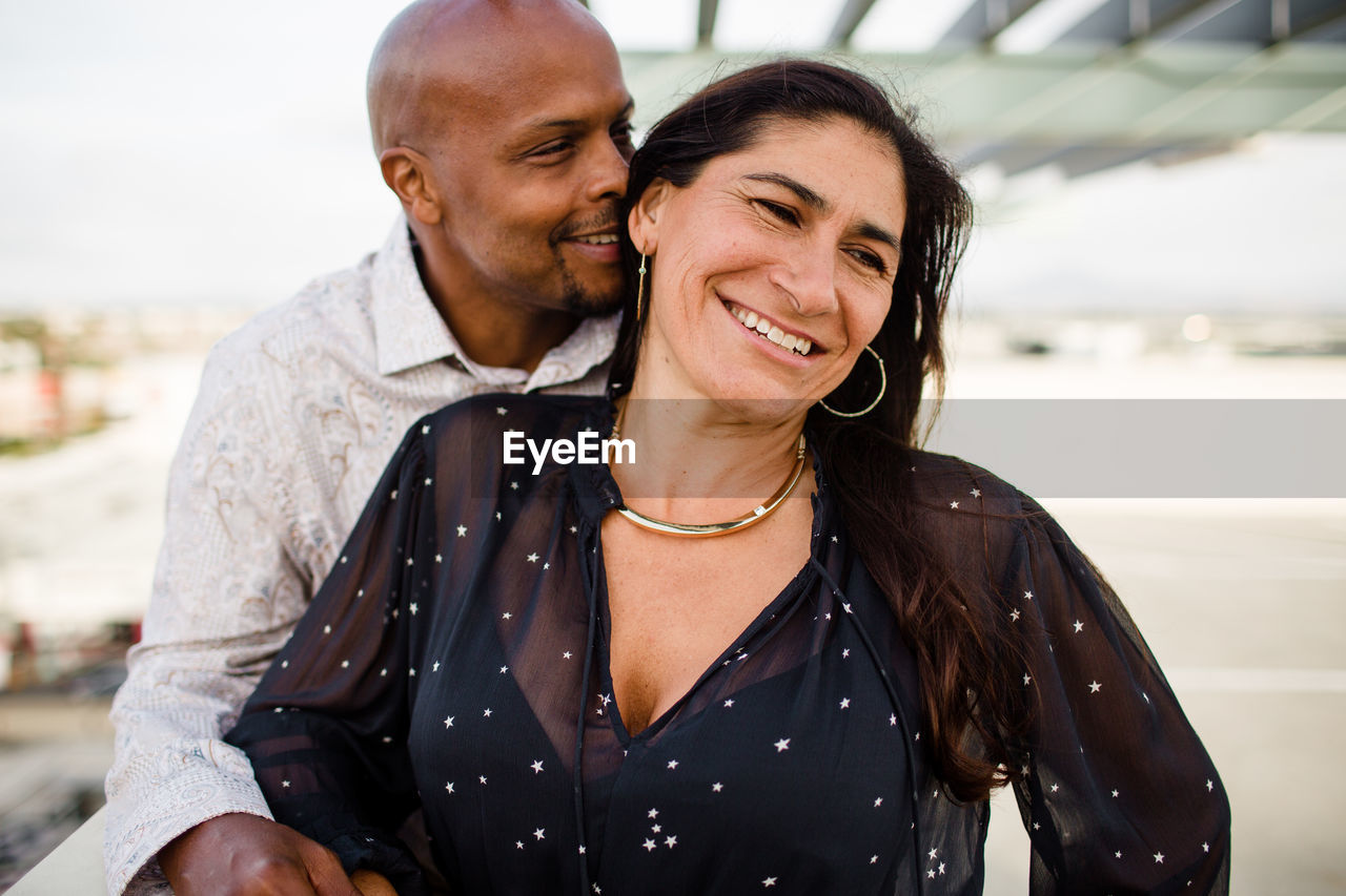 Multiracial late forties couple embracing at sunset in san diego